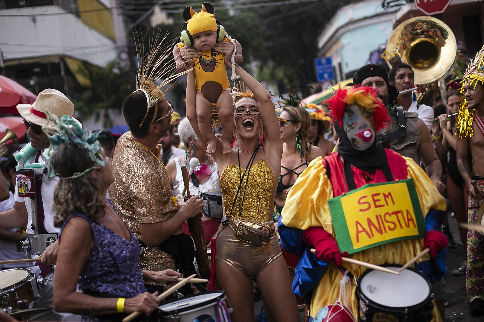 A woman holds up her son, dressed as Simba from the Lion King, during the "Ceu na Terra" or Heaven on Earth pre-Carnival street party, in Rio de Janeiro, Brazil, Saturday, Feb. 3, 2024. (AP Photo/Bruna Prado)