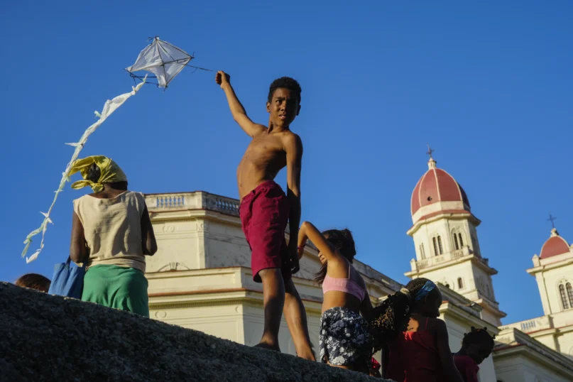 A youth flies a kite outside the shrine of the Virgin of Charity of Cobre in El Cobre, Cuba, on Saturday, Feb. 10, 2024. (AP Photo/Ramon Espinosa)