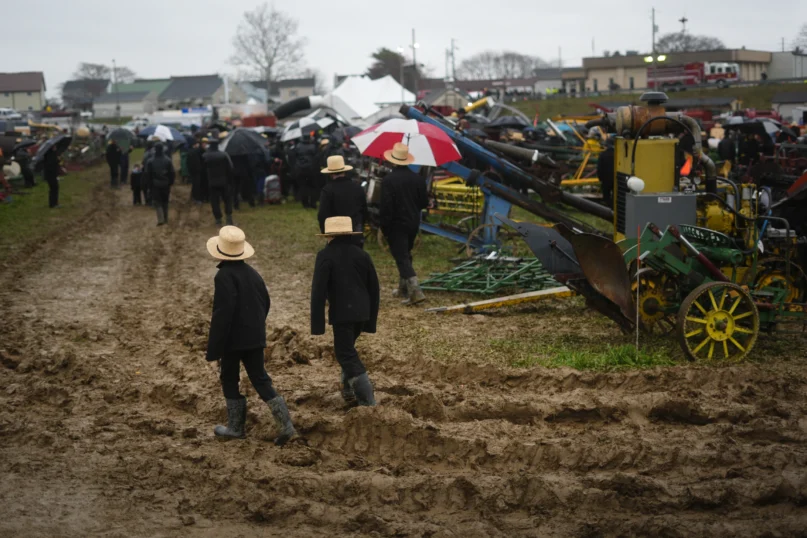 People walk in mud during an auction at the 56th annual mud sale to benefit the local fire department in Gordonville, Pa., Saturday, March 9, 2024. (AP Photo/Matt Rourke)