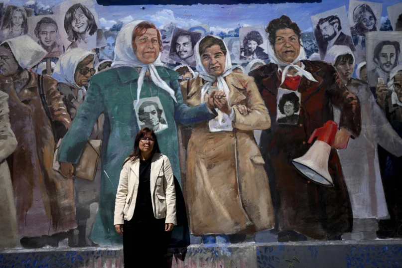 Claudia Poblete poses for a photo in front of a mural depicting the Mothers of Plaza de Mayo group, at the former Navy School of Mechanics, known as ESMA, now a human rights museum, in Buenos Aires, Argentina, Friday, March 22, 2024. (AP Photo/Natacha Pisarenko)