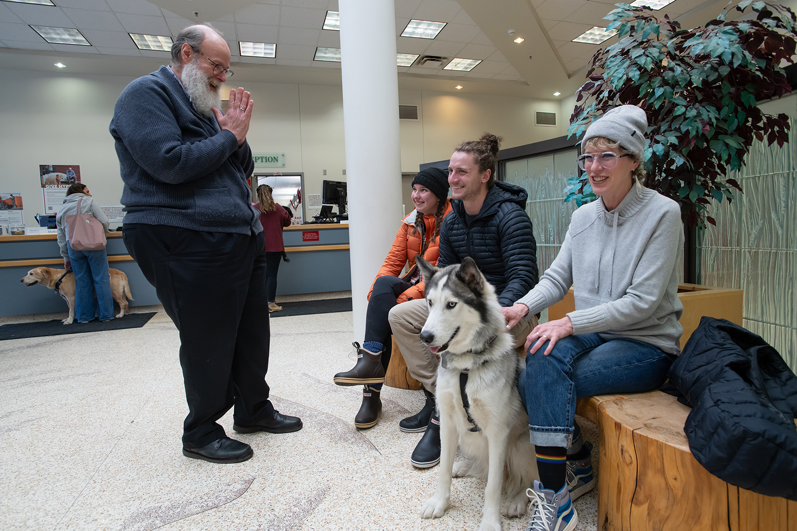Scott Campbell, left, the veterinary chaplain at Washington State University's College of Veterinary Medicine, visits with Olivia and Phinehas Lampman, center, owners of Goose, a Husky mix dog, as Phinehas’ mother and WSU Honors College Associate Professor Annie Lampman, right, looks on, Wednesday, Jan. 10, 2024, in the lobby of the Veterinary Teaching Hospital in Pullman. (College of Veterinary Medicine/Ted S. Warren)