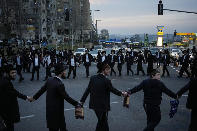 Ultra-Orthodox Jewish men and boys dance and sing while blocking a road during a protest against the country’s military draft in Jerusalem, Feb. 26, 2024. (AP Photo/Leo Correa)