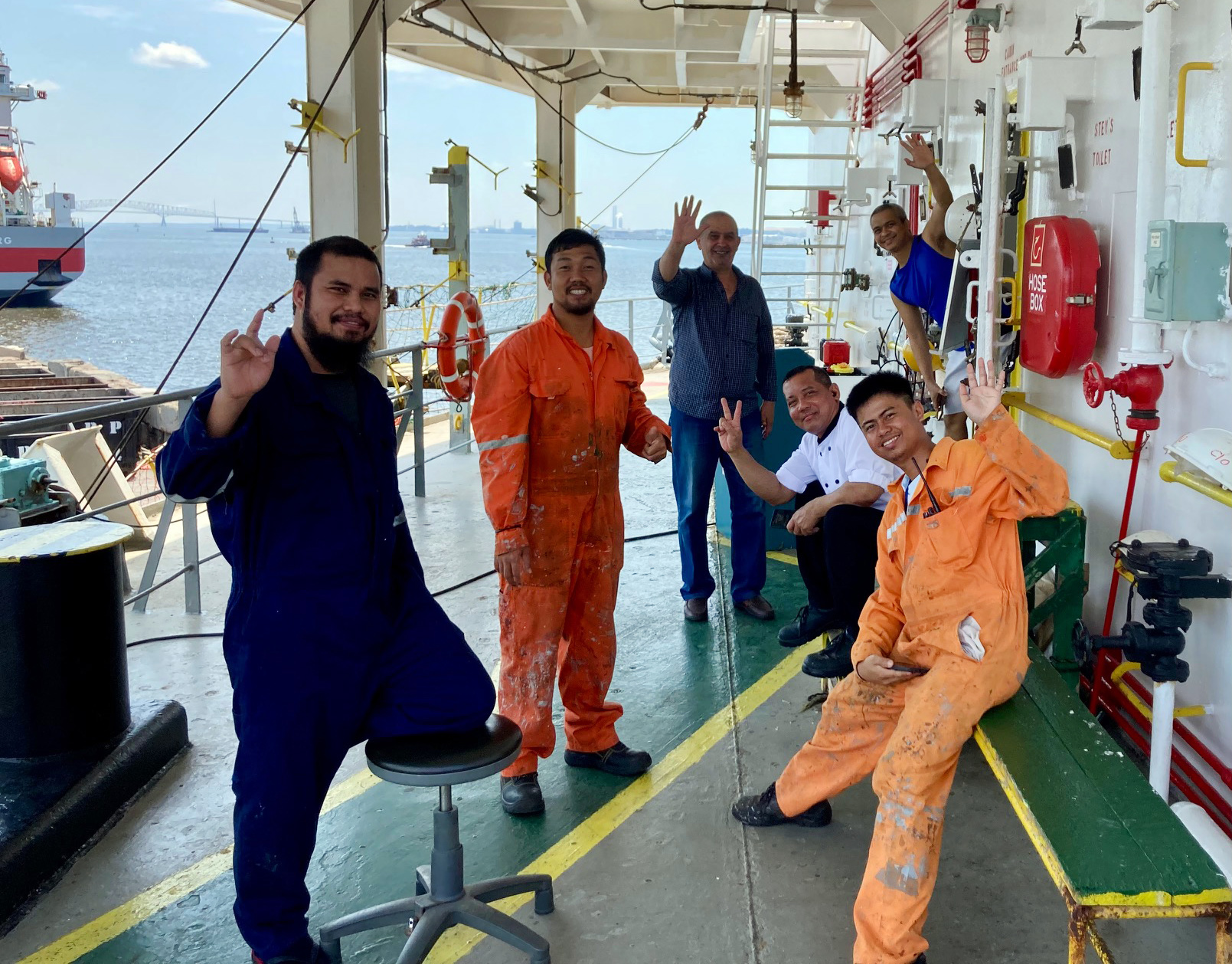 A crew of seafarers aboard their ship docked at the Port of Baltimore in Maryland. The Francis Scott Key Bridge is visible in the top left of the photo. (Photo by Maggie Schorr)