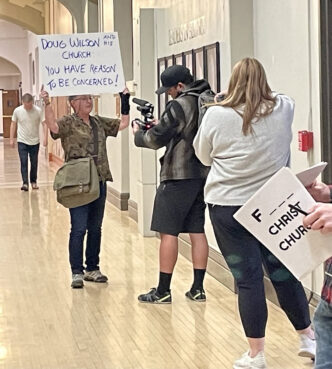 Keely Emerine-Mix, left, protests before a town hall meeting with Christ Church on Thursday, April 11, 2024, in Moscow, Idaho. (Photo by Tracy Simmons/FāVS News)