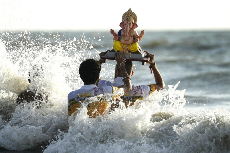 Devotees immerse an idol of elephant-headed Hindu god Ganesha in the Arabian Sea, during the ten-day-long Ganesh Chaturthi festival in Mumbai, India, Sunday, Sept. 8, 2024. (AP Photo/Rafiq Maqbool)