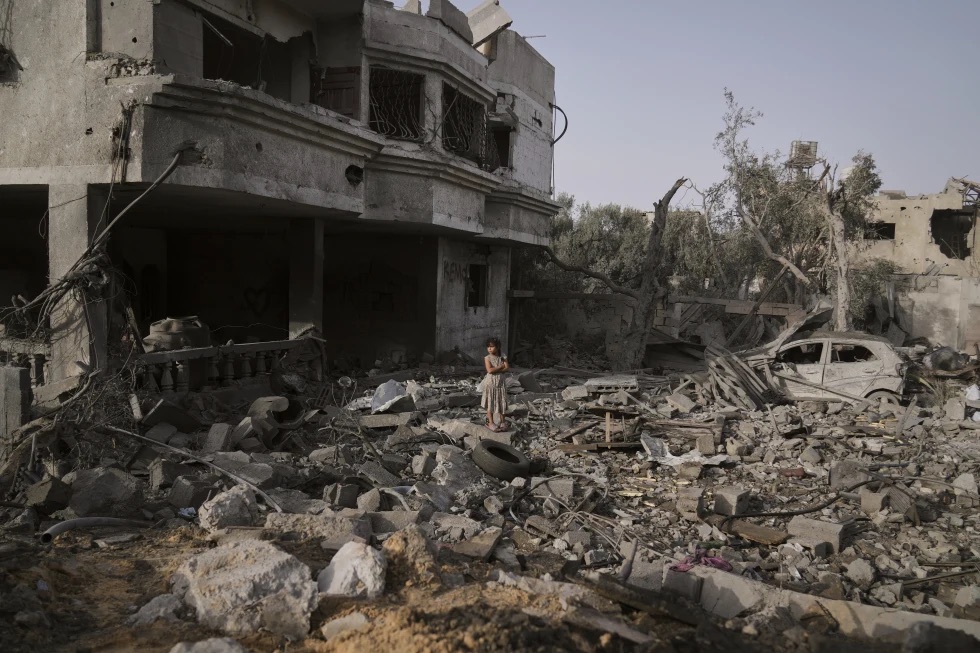 A Palestinian girl stands atop the rubble